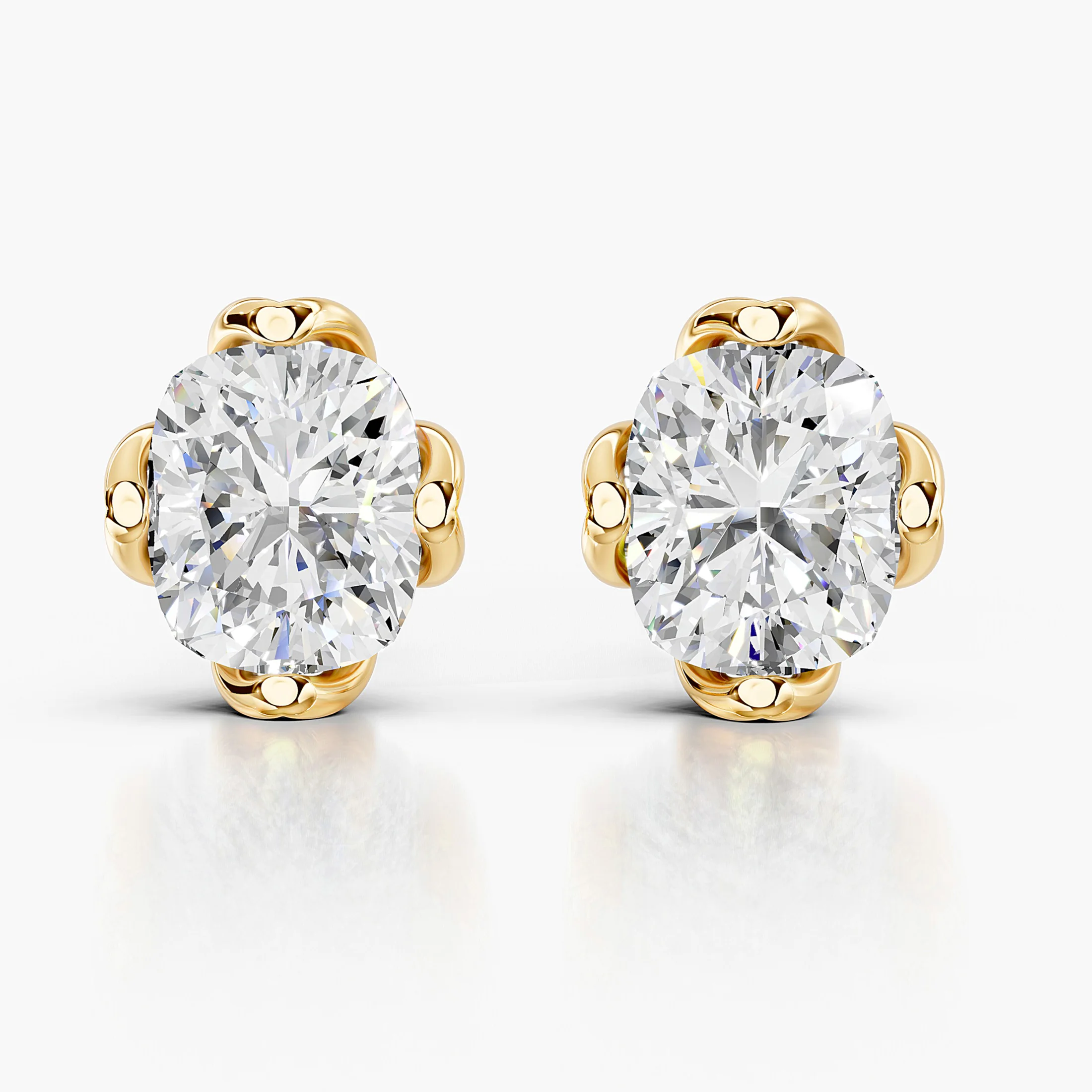 Cushion-cut diamond solitaire stud earrings with sculpted four-prong settings.
